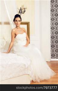 Beautiful Bride. beautiful young woman in wedding dress sitting on bed