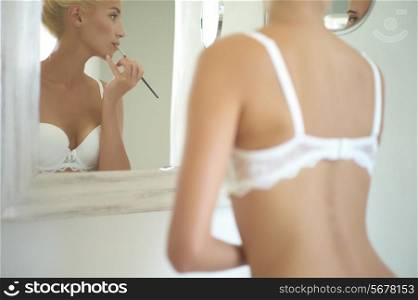 Beautiful bride in the mirror corrects make-up. Fashion art photo