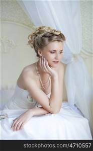 Beautiful bride in white wedding dress at home