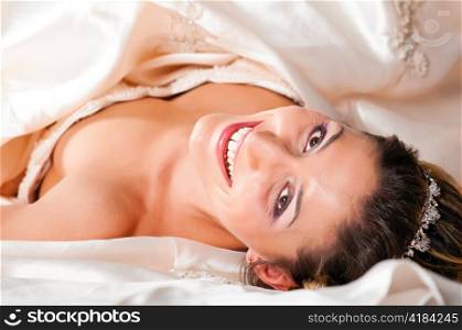 beautiful bride is lying on floor in wedding dress and looking at camera