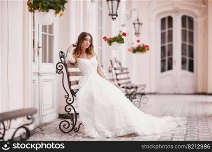 Beautiful bride is sitting on wooden bench in old city. young woman with long hair in lace satin wedding dress in ancient town. Smile and love. wedding day.. Beautiful bride is sitting on wooden bench in old city. young woman with long hair in lace satin wedding dress in ancient town. Smile and love. wedding day