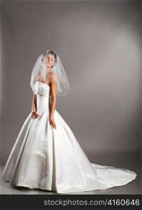 beautiful bride is standing in wedding dress on grey background