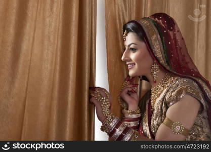 Beautiful bride looking through curtains