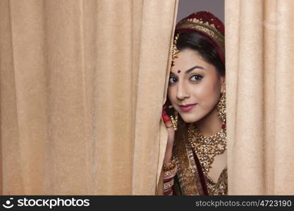 Beautiful bride peeping through curtains