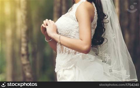 Beautiful bride stand waiting bridegroom outdoors in a forest