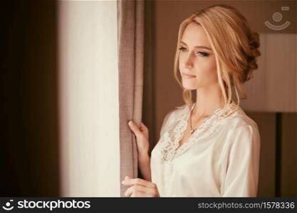 Beautiful bride standing near the window and smiling. Wedding Day.. Beautiful bride standing near the window and smiling. Wedding Day