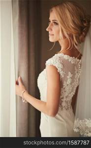 Beautiful bride standing near the window and smiling. Wedding Day.. Beautiful bride standing near the window and smiling. Wedding Day