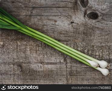 Beautiful, bright garlic stalks on unpainted desk. Place for your inscription. Top view, close-up. Concept of delicious and healthy food. Beautiful, bright garlic stalks on unpainted desk