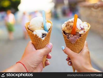 Beautiful bright ice cream with different flavors in the hands of a couple.. Beautiful bright ice cream with different flavors in the hands of a couple