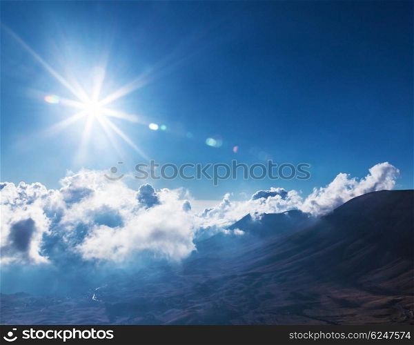 Beautiful bright sun in blue cloudy sky over high mountains, stunning cloudscape, natural background, fresh air, summer time