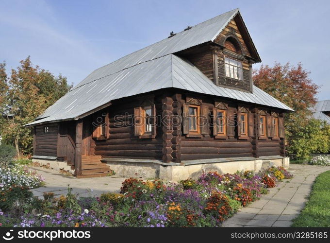 Beautiful brown wooden house with flower bed in Pokrovsky Monastery of Suzdal, Russia