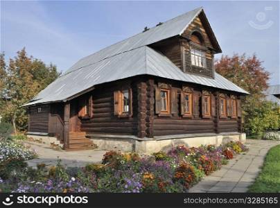 Beautiful brown wooden house with flower bed in Pokrovsky Monastery of Suzdal, Russia