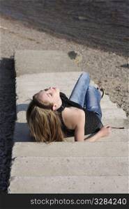 Beautiful brunet woman lying on the steps near the river