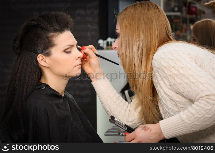 Beautiful brunette, applying perfect makeup to her face