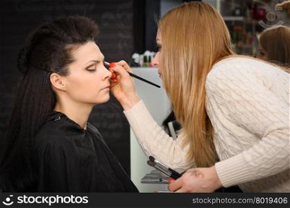 Beautiful brunette, applying perfect makeup to her face