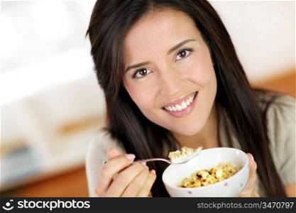 Beautiful brunette eating cereals in the morning