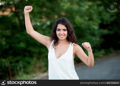 Beautiful brunette girl celebrating something in the park wiht many plants of background