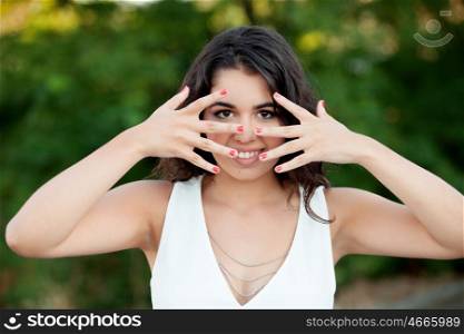 Beautiful brunette girl covering her face in the park wiht many plants of background