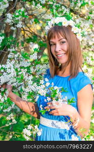 Beautiful brunette girl near a blossoming cherry tree