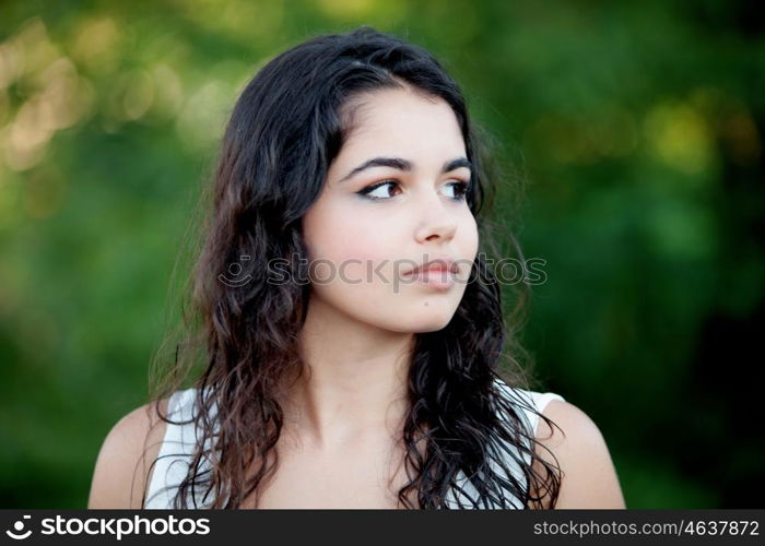 Beautiful brunette girl relaxing in the park wiht many plants of background