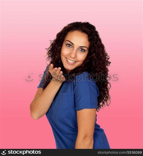 Beautiful brunette girl sending a kiss isolated on a over pink background