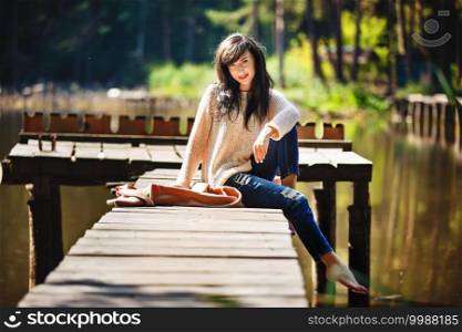 beautiful brunette girl sitting on the old bridge barefoot by the river. nature.. beautiful brunette girl sitting on the old bridge barefoot by the river. nature
