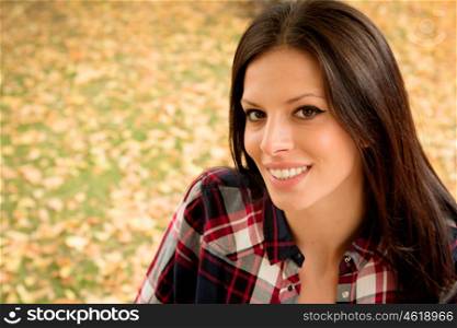 Beautiful brunette girl taking a walk by a park in autumn