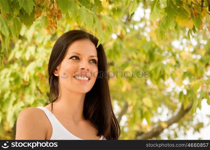 Beautiful brunette girl taking a walk by a park in autumn
