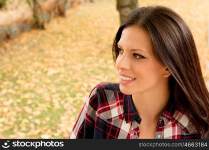 Beautiful brunette girl taking a walk by a park in autumn