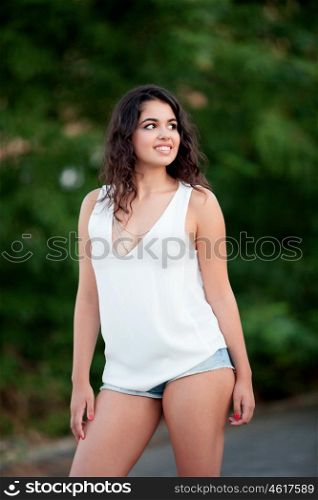 Beautiful brunette girl with shorts relaxing in the park wiht many plants of background