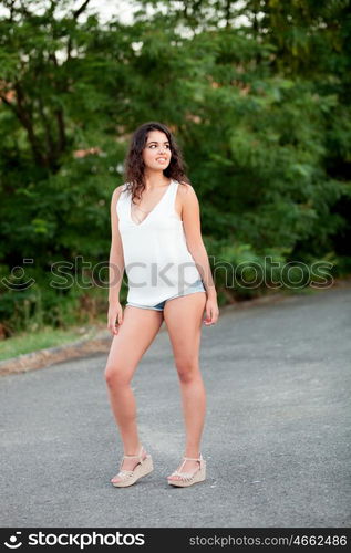 Beautiful brunette girl with shorts relaxing in the park wiht many plants of background