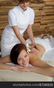 Beautiful brunette having back massage at luxury spa centre