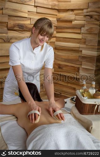 Beautiful brunette having wooden brush massage at luxury spa