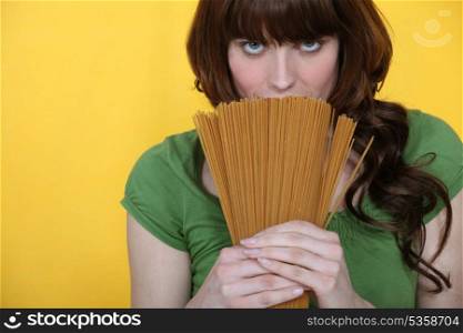 beautiful brunette holding spaghettis isolated on yellow