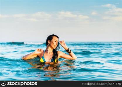 Beautiful brunette in the sea at sunset
