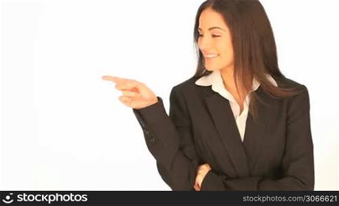 Beautiful brunette laughing businesswoman pointing to the side of the frame with her finger towards blank copyspace