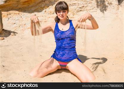 beautiful brunette playing with sand on the beach