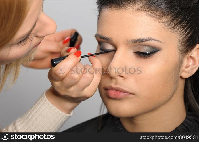 Beautiful brunette portrait, applying perfect makeup to her face