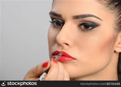 Beautiful brunette portrait, applying perfect makeup to her lips