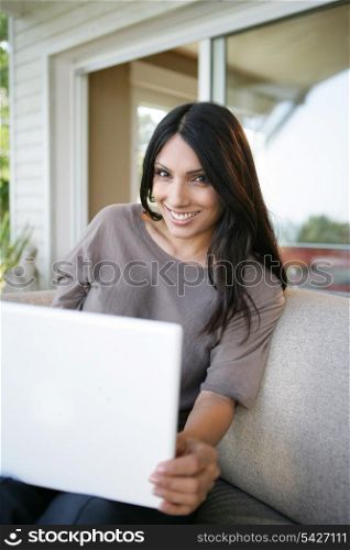 beautiful brunette sitting in the back yard with her laptop