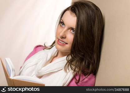 Beautiful brunette student woman holding book wear pink jumper