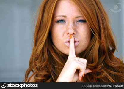 beautiful brunette with a finger on her lips showing to keep silence