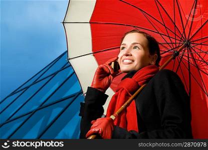 Beautiful brunette with red umbrella talking on the phone