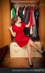 Beautiful brunette woman choosing dresses in big wardrobe