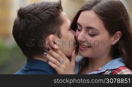 Beautiful brunette woman embracing her beloved boyfriend and looking at him with love and tenderness. Closeup. Romantic young couple bonding with each other, expressing their feelings with sensual kiss and gentle stroking.