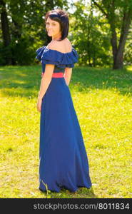beautiful brunette woman in a long dress in the park