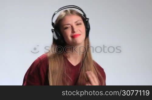 Beautiful brunette woman in big earphones wearing red lipstick enjoying her favorite music on mp3 player. Excited positive girl with amazing long hair in cheerful mood going crazy and having fun while listening music.