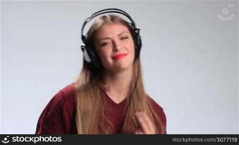 Beautiful brunette woman in big earphones wearing red lipstick enjoying her favorite music on mp3 player. Excited positive girl with amazing long hair in cheerful mood going crazy and having fun while listening music.