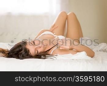 beautiful brunette woman in sexy lingerie lying down in bed indoors shot pretty light one women long hair