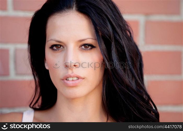 Beautiful brunette woman looking at camera with red brick wall background